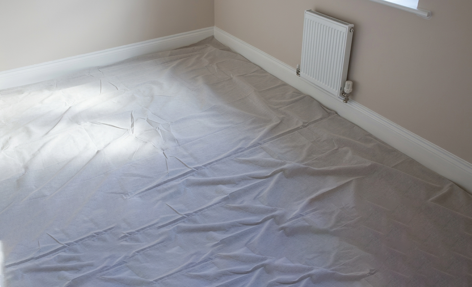 Room floor covered with laminated twill dust sheets for protection during painting or renovation.